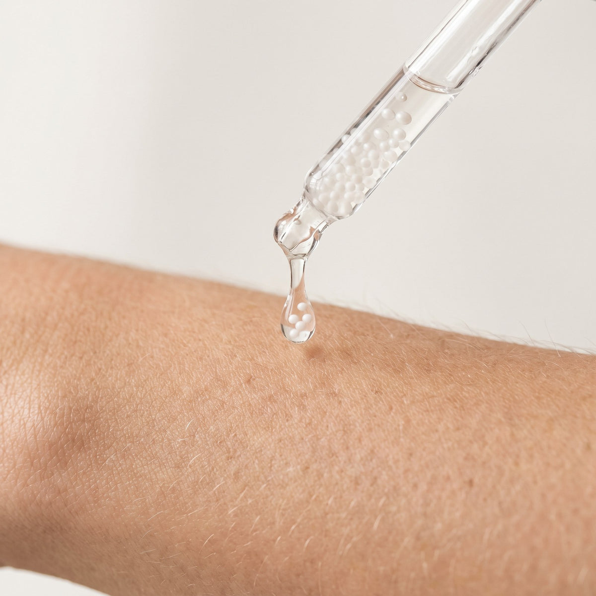 Clear serum with visible brightening capsules dropping onto skin